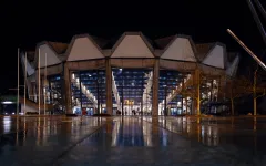 Das helle erleuchtete Audimax im Dunklen, Personen gehen darauf zu.